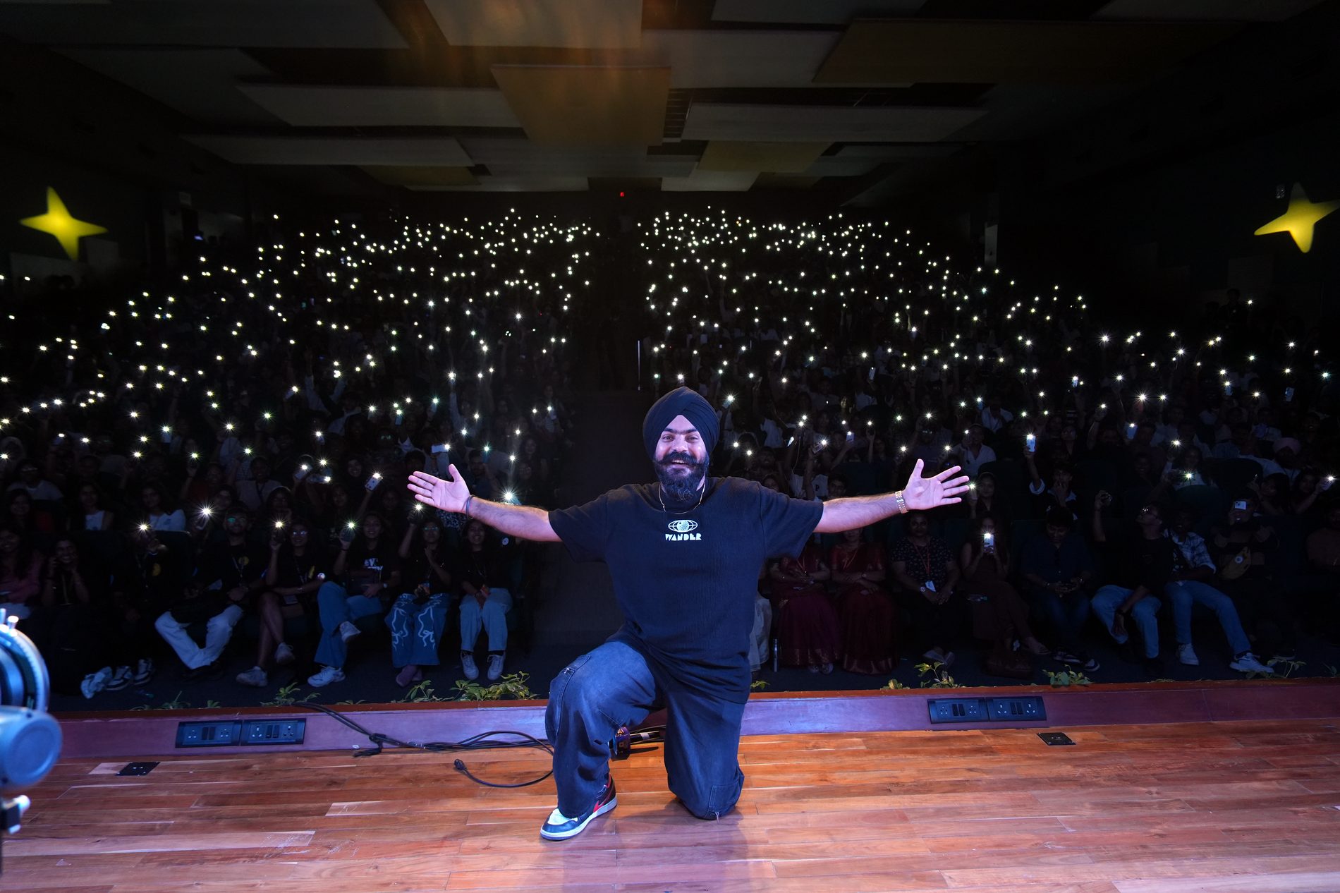 Arms wide, phone lights across the crowd